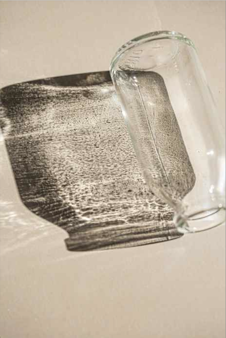 A close up picture of light and shadow reflecting through a clear glass jar.