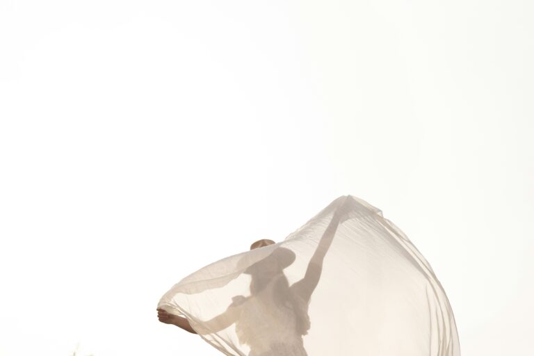 Woman obscured by fabric blowing in a breeze.